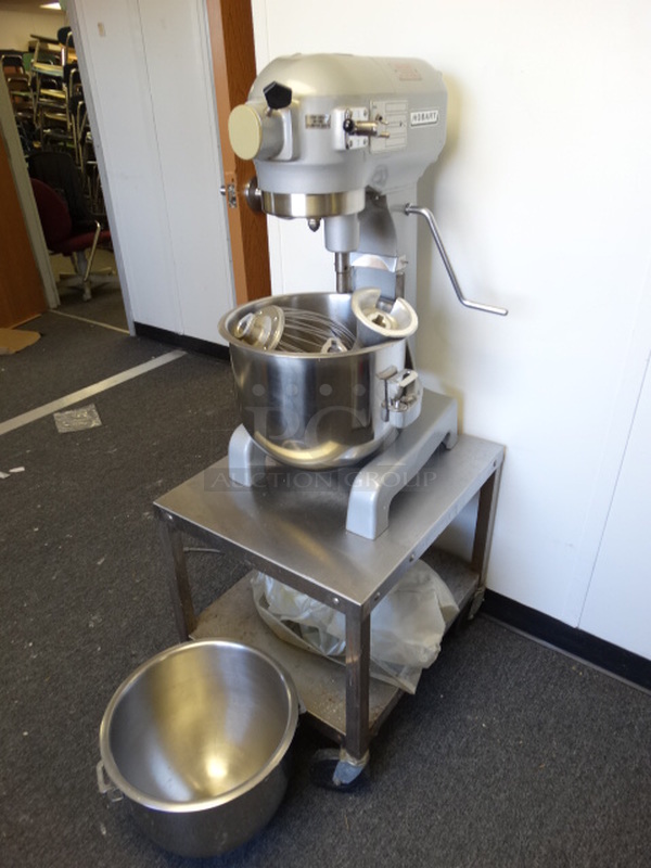 BEAUTIFUL! Hobart Model A-200 Metal Commercial Countertop 20 Quart Planetary Mixer w/ 2 Stainless Steel Mixing Bowls, Dough Hook, Paddle, Whisk Attachments, Cover and Equipment Stand w/ Commercial Casters. 115 Volts, 1 Phase. Mixer 15x18x31. Stand 20x24x22. (Hallway)