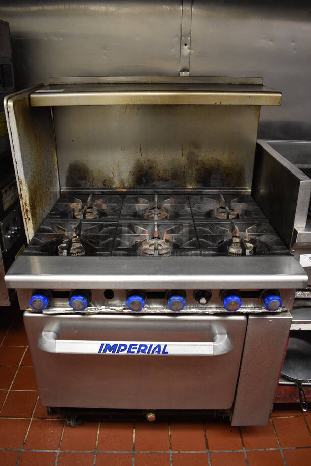 BEAUTIFUL! Imperial Stainless Steel Commercial Propane Gas Powered 6 Burner Range w/ Lower Oven and Overshelf on Commercial Casters. This Unit Will Be Professionally Uninstalled. 36x32x57. Tested and Working!