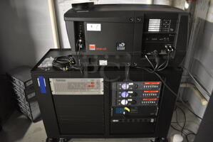 MARVELOUS! 2012 Barco Model DP2K-12C Commercial Countertop DLP Cinema Projector on Cabinet w/ Film-Tech FT21 Automation Cinema System, 4 Dolby CP750 Digital Cinema Processors, DCM Powercom, TV Monitor and Tripp Lite Surge Protector. 200-240 Volts. See Lot 6 For Additional Pictures! 26x38x22, 24x53x38. BUYER MUST REMOVE. Tested and Working!