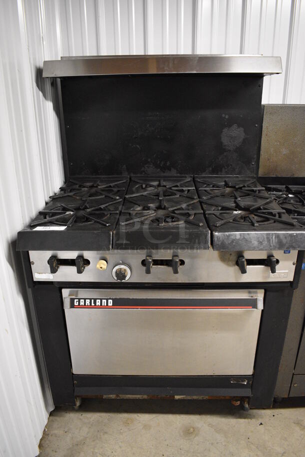 NICE! Garland Stainless Steel Commercial Gas Powered 6 Burner Range w/ Lower Oven and Stainless Steel Overshelf. 36x31x59 - Image 1 of 5