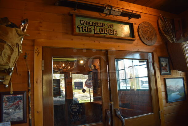 ALL ONE MONEY! Lot of Wall Decorations Including Welcome to the Lodge Sign, Bag, Walking Stick, United States of America Sign and Basket. BUYER MUST REMOVE - Image 1 of 7