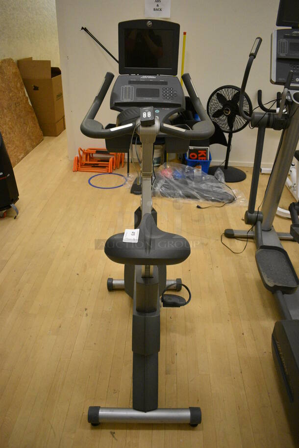 Life Fitness Metal Commercial Floor Style Upright Stationary Bicycle w/ Life Fitness Monitor. BUYER MUST REMOVE. 24x48x63. Working Condition Is Not Known. (behind squash court - right)