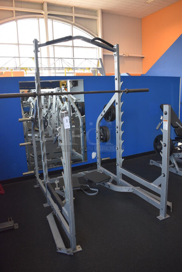 NICE! Hammer Strength Gray Metal Floor Style Squat Rack w/ Olympic Bar. Does Not Include Weight Plates. BUYER MUST REMOVE - Unit May Need Disassembly For Removal. 65x73x91. (weight room) - Image 1 of 9