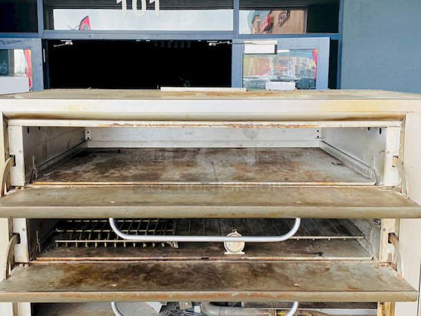 PRISTINE!! Blodgett 981 Natural Gas Multi-Purpose Double Deck Oven with Draft Diverter - 100,000 BTU. On Commercial Casters.    Can be used for: roasts, pastries, cakes, artesian breads, pizzas, and more 42"W x 32"D deck interior, (4) sections, consists of (4) 7" high baking compartments per section, (FTDO) 200-500°F mechanical thermostat, counter-balanced doors with heavy chrome handle, angle iron frame, steel deck, crown angle trim, aluminized steel interior, stainless steel top, front, sides and back  Overall Dimensions: Width: 60" Depth: 38 1/2" Height: 68 13/16" Interior Dimensions (Per Oven): Width: 42" Depth: 32" Height: 7" Deck Thickness: 1" - Image 5 of 11