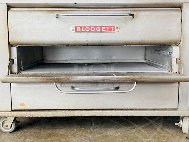 PRISTINE!! Blodgett 981 Natural Gas Multi-Purpose Double Deck Oven with Draft Diverter - 100,000 BTU. On Commercial Casters.    Can be used for: roasts, pastries, cakes, artesian breads, pizzas, and more 42"W x 32"D deck interior, (4) sections, consists of (4) 7" high baking compartments per section, (FTDO) 200-500°F mechanical thermostat, counter-balanced doors with heavy chrome handle, angle iron frame, steel deck, crown angle trim, aluminized steel interior, stainless steel top, front, sides and back  Overall Dimensions: Width: 60" Depth: 38 1/2" Height: 68 13/16" Interior Dimensions (Per Oven): Width: 42" Depth: 32" Height: 7" Deck Thickness: 1" - Image 9 of 11
