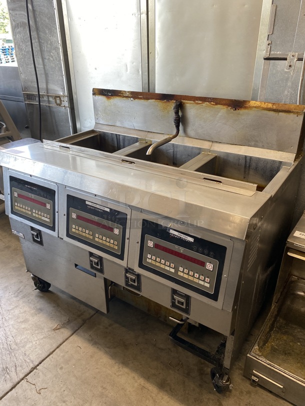 Henny Penny Model OFG-323 Stainless Steel Commercial Propane Gas Powered 3 Bay Deep Fat Fryer w/ Filtration System on Commercial Casters. 255,000 BTU. 49.5x33.5x45