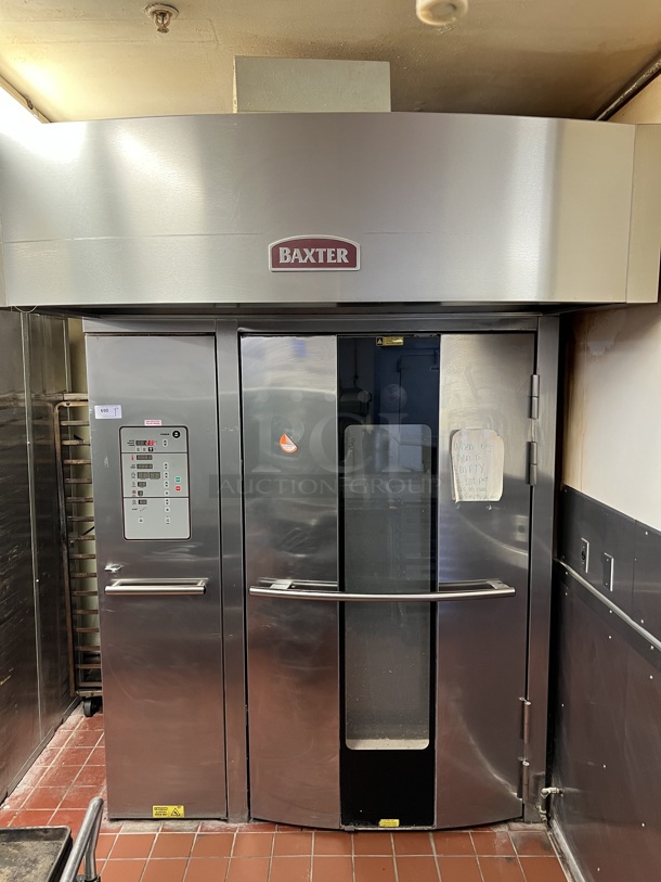 Baxter Stainless Steel Commercial Natural Gas Powered Floor Style Single Door Roll In Rotating Double Rack Oven w/ Attached Hood and 2 Metal Pan Racks. BUYER MUST REMOVE. 208-240 Volt, 3 Phase Controls. 73x97x99.5. Unit Was In Working Condition When Restaurant Closed. (bakery kitchen)