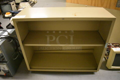 Tan Metal Bookshelf. 34.5x12.5x29. (south basement 012)