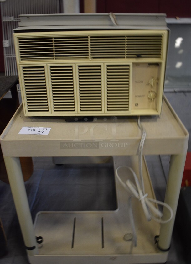 Window Mount Air Conditioning Unit on Tan Poly 2 Tier Cart on Casters. 24x36x27, 20x20x14. (Middle School Gym)