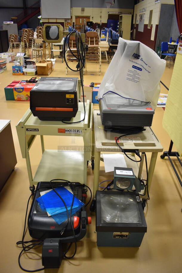 ALL ONE MONEY! Lot of 2 Tan Carts w/ 4 Various Overhead Projectors; 3M and Bell E Howell. Includes 14x17x27. (Chipperfield Elementary Gym)