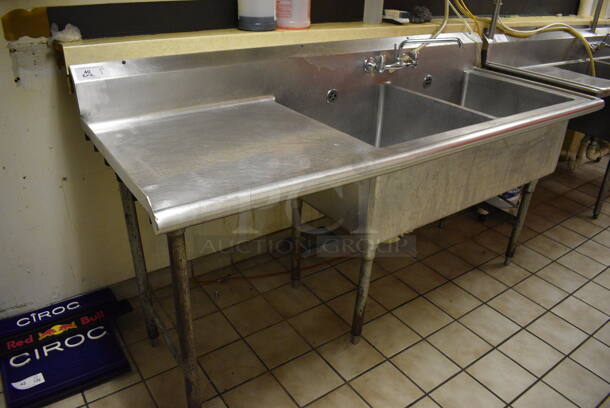 Stainless Steel Commercial 2 Bay Sink w/ Left Side Dual Drain Board, Faucet, Handles. BUYER MUST REMOVE. 79x30x42.5. Bays 23x24x14. Drain Board 28x26x1. (dishwasher area)