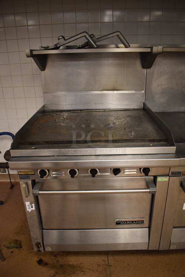Garland M47R Stainless Steel Commercial Floor Style Natural Gas Powered Flat Top w/ Oven, Over Shelf and Back Splash. BUYER MUST REMOVE. 34x38x58. (Education Kitchen 2)