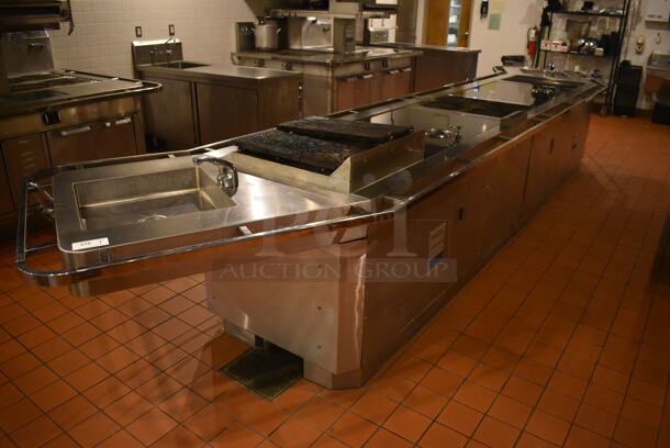 Viking Stainless Steel Commercial Gas Powered Prep Station w/ 2 Sinks, 2 4 Burner Grills, 2 Drawer Cooler, Oven, 2 4 Burner Induction Ranges and Charbroiler. BUYER MUST REMOVE. 240x46x41. Tested and Working! (Demo Kitchen)