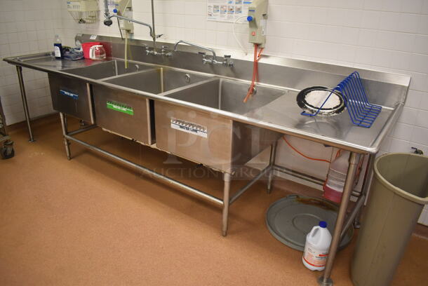 Stainless Steel Commercial 3 Bay Sink w/ Dual Drain Boards, 2 Faucets, 2 Handle Sets and Spray Nozzle Attachment. BUYER MUST REMOVE. 134x36x48. Bays 24x30x14. Drain Boards 28x32x2. (Restaurant Kitchen) - Image 1 of 7
