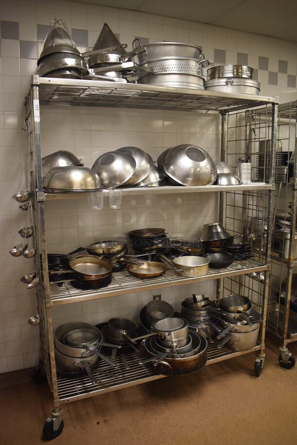 Metal 4 Tier Wire Shelving Unit on Commercial Casters w/ Contents Including Metal Bowls, Skillets and China Cap Strainers. BUYER MUST DISMANTLE. PCI CANNOT DISMANTLE FOR SHIPPING. PLEASE CONSIDER FREIGHT CHARGES. 60x24x78. (Education Kitchen 2)