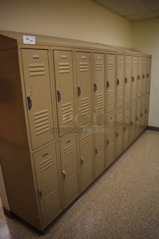 Wall of 22 Tan Metal Lockers. BUYER MUST REMOVE. 132x18x71. (Womens Locker Room)