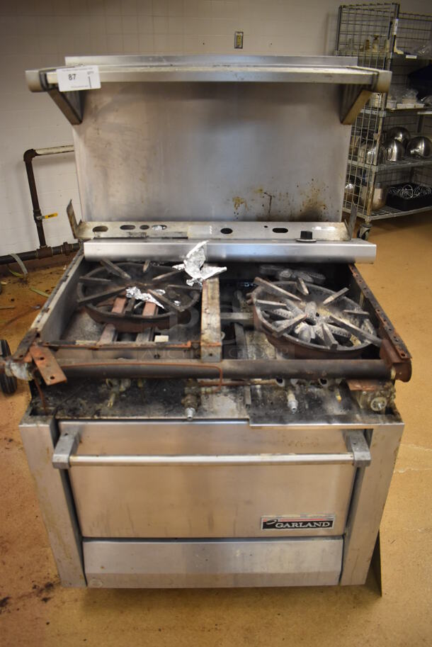 Garland M42-6R Stainless Steel Commercial Natural Gas Powered 2 Burner Range w/ Flat Top, Oven, Over Shelf and Back Splash. BUYER MUST REMOVE. 34x38x58. For Parts. (Education Kitchen) - Image 1 of 8