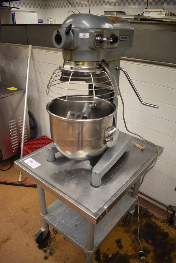 Hobart A200 Metal Commercial Countertop 20 Quart Planetary Dough Mixer w/ 2 Metal Mixing Bowls, Bowl Guard and Paddle Attachment on Stainless Steel Equipment Stand on Commercial Casters. 115 Volts, 1 Phase. 16x23x30, 24x30x29. Tested and Working! Metal Commercial Gas Powered Single Door Smoker on Commercial Casters. BUYER MUST REMOVE. 22x30x56. Tested and Working! (Restaurant Kitchen)