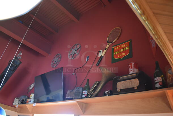 ALL ONE MONEY! Shelf Lot of Various Items Including Bottles and Helmet and Wall Decor Above The Shelf. Does Not Include The Shelf Itself or The Television. BUYER MUST REMOVE. (Dining Room) - Image 1 of 4