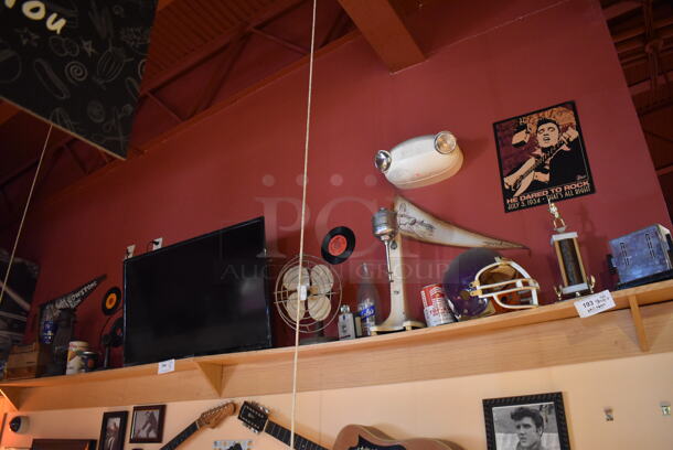 ALL ONE MONEY! Shelf Lot of Various Items Including Helmet, Fan and Trophy and Wall Decor Above The Shelf. Does Not Include The Shelf Itself or The Television. BUYER MUST REMOVE. (Dining Room) - Image 1 of 5