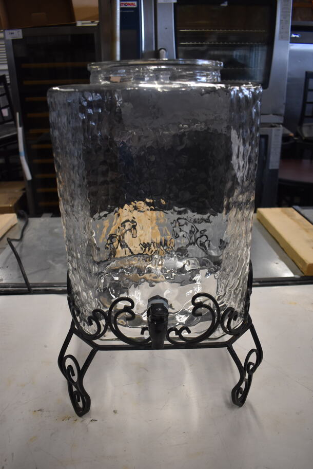 Large Textured Glass Beverage Dispenser Without Top on Black Decorative Stand.