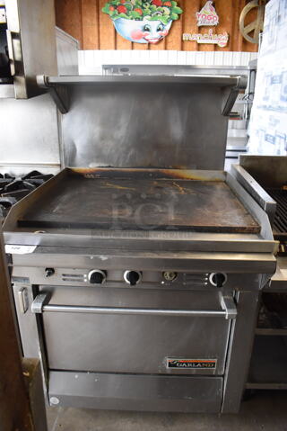 Garland Natural Gas Powered Commercial Stainless Steel Oven With Steel Racks And Top Griddle With Overshelf On Galvanized Legs. 