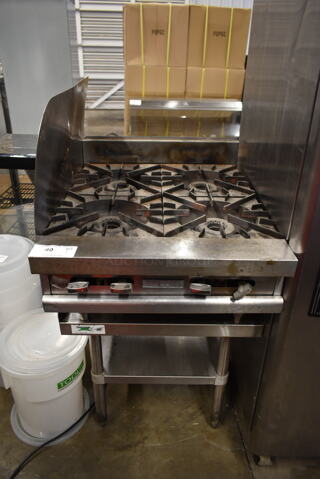 Vulcan Stainless Steel Commercial Countertop Natural Gas Powered 4 Burner Range w/ Left Side Splash Guard on Regency 600ES2424S Stainless Steel Equipment Stand w/ Under Shelf.