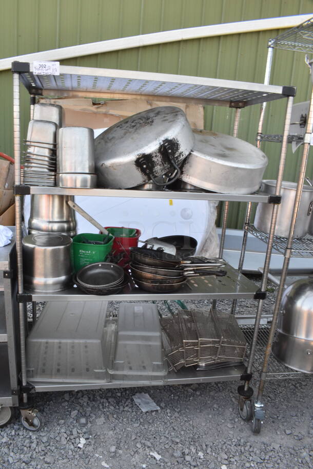 Chrome Finish 4 Tier Wire Shelving Unit on Commercial Casters w/ Contents Including Metal Stock Pots, Stainless Steel Drop In Bins, Metal Fry Baskets, Skillets. BUYER MUST DISMANTLE. PCI CANNOT DISMANTLE FOR SHIPPING. PLEASE CONSIDER FREIGHT CHARGES. - Image 1 of 1