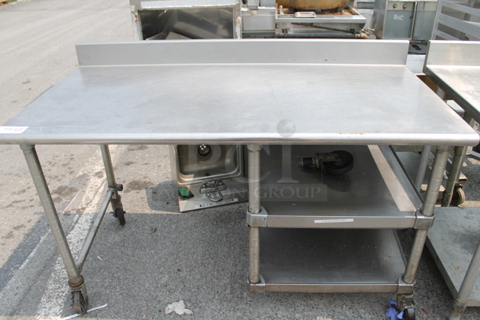 Stainless Steel Commercial Table w/ Back Splash and 2 Under Shelves on Commercial Casters. One Caster Needs To Be Reattached.