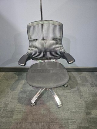 Black webbed-back office chair. Has armrests and a cushioned black seat. Sits on a silver metal frame on black wheels. In fair used condition. No rips or tears. Measures 43” H x 28” W.  

