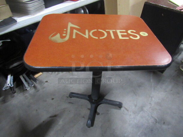 One Brown Table Top  With The NOTES Logo, On A Pedestal Base. 30X24X30
