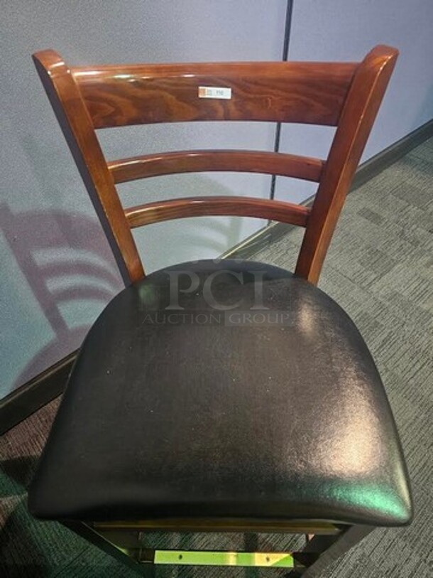 Bar height wooden chairs with black leather seat. In very good condition- no broken pieces. Slight scratches in some places, but still in good shape with lots of life left!  17.5” W x 43” H x 16” D. BIDX3 - Image 1 of 1