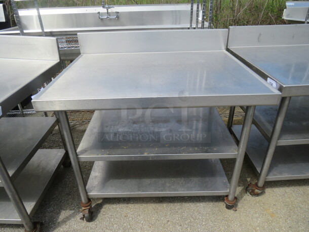 One Stainless Steel Table With 2 Stainless Steel Undershelves, And Back Splash, On Casters. 42X32X40