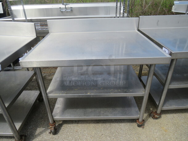 One Stainless Steel Table With 2 Stainless Steel Undershelves, And Back Splash, On Casters. 42X32X40 - Image 1 of 1
