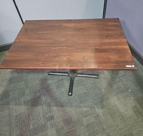 Restaurant style table with a black metal base and a dark grained wooden top. A solid table in good condition! Some scratching on base that can be cleaned up. 29” H x 48” W x 29.5” D.  

  - Image 1 of 2