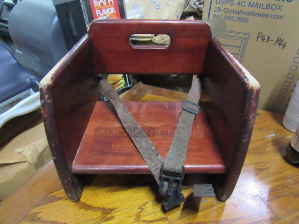 One Wooden Booster Seat With Safety Straps.