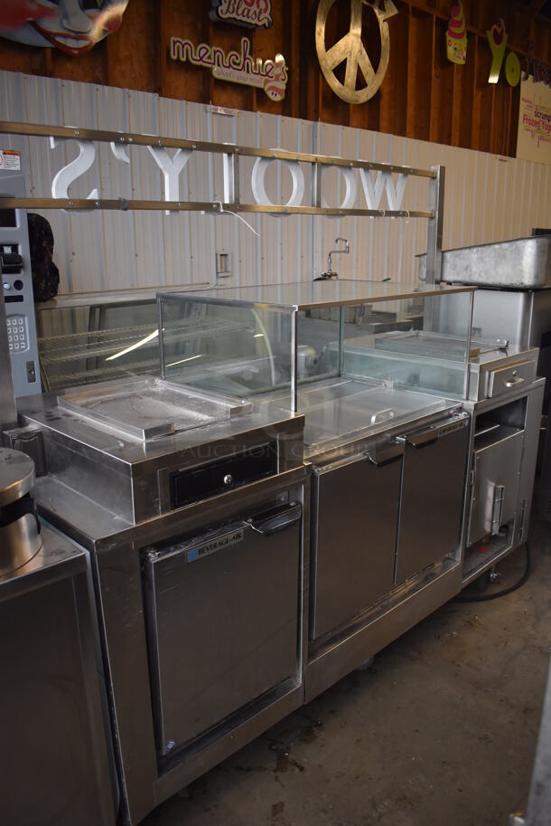 Stainless Steel Commercial Portable Shaved Ice Prep Station Stand w/ Beverage Air UCF20 Single Door Undercounter Freezer, Beverage Air UCR34Y 2 Door Cooler w/ Glass Top Case and Sneeze Guard on Commercial Casters. 208-250 Volts, 1 Phase. 85x30x73