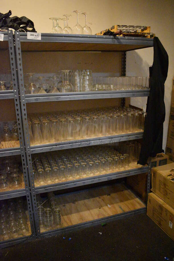 Gray Metal 5 Tier Shelving Unit w/ Contents Including Beverage Glasses and Wine Glasses. 48x24x72. BUYER MUST REMOVE; BUYER MUST DISMANTLE. PCI CANNOT DISMANTLE FOR SHIPPING. PLEASE CONSIDER FREIGHT CHARGES. (glass room - off of bar area)