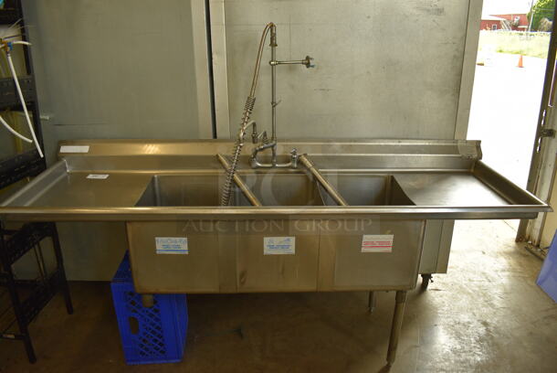 Stainless Steel Commercial 3 Bay Sink w/ Dual Drainboards, Faucet, Handles and Spray Nozzle Attachment. 2 Legs Need To Be Reattached. 87x27x39. Bays 16x21x14. Drainboards 18x24x2