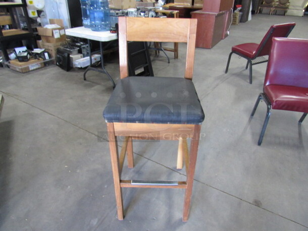Wooden Bar Height Chair With A Black Cushioned Seat And Footrest. 3XBID.