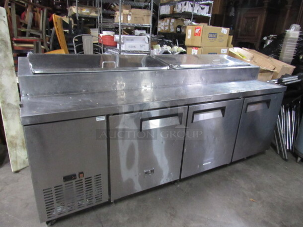 One Stainless Steel  Kelvinator 3 Door Refrigerated Prep Table With 3 Racks On Casters. Model# KCPT92.12. 92X33X42 - Image 1 of 3