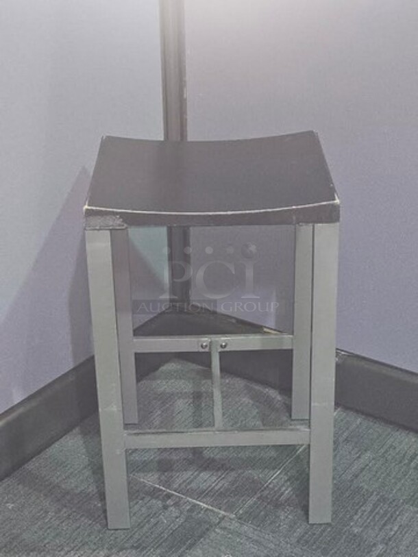 Stools. Silver finish metal framing with wooden black seat. Has wear and scratches on the seat as well as some on the frame but in good condition! Measures 24.5” H x 15.5” W x 14” D. BIDX8

 - Image 1 of 2