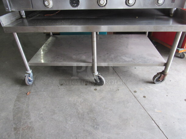One Stainless Steel Equipment Table With Stainless Under Shelf, R/L And Back Splash, On Casters. 60X36X28.5