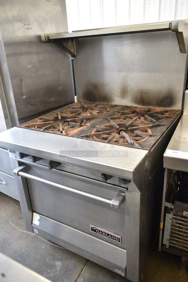 Garland M44R Stainless Steel Commercial Natural Gas Powered 4 Burner Range w/ Oven, Over Shelf and Back Splash on Commercial Casters.  - Image 1 of 9