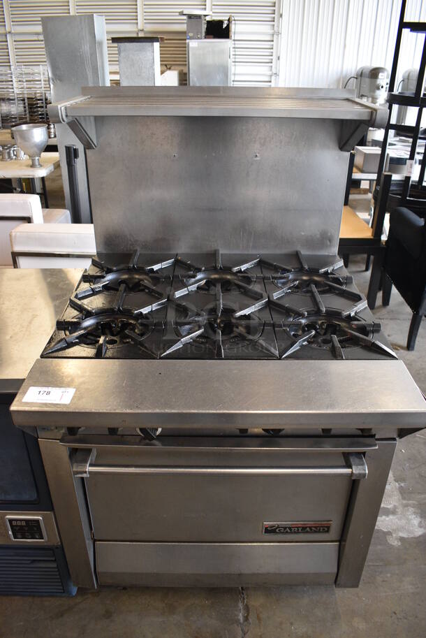 Garland Stainless Steel Commercial Natural Gas Powered 6 Burner Range w/ Oven, Over Shelf and Backsplash on Commercial Casters. 34x38x56