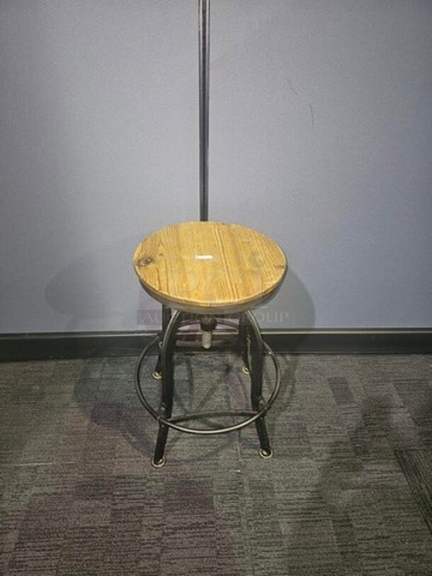 Single wooden stool with black metal base and wooden seat. In good condition- signs of wear but still solid and has life left! 26” H x 15” W x 18” D.  

 - Image 1 of 2