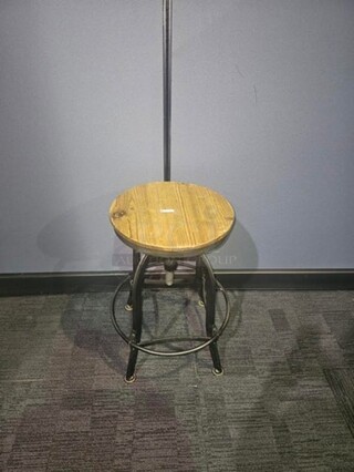 Single wooden stool with black metal base and wooden seat. In good condition- signs of wear but still solid and has life left! 26” H x 15” W x 18” D.  


