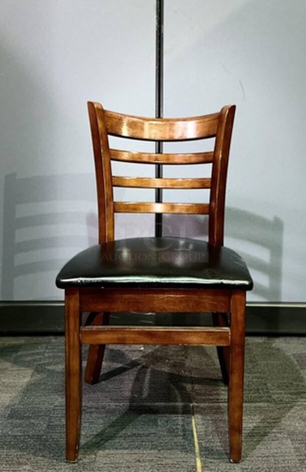 Wooden restaurant chair with black leather seat- 18.5" W x 33.5" L x 15" D. In good used condition, no broken pieces but have some marks and scuffs from normal wear. BIDX6 - Image 1 of 3