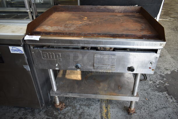 Lang G-3E Stainless Steel Commercial Natural Gas Powered Flat Top Griddle w/ Metal Under Shelf on Commercial Casters. 27,000 BTU.  - Image 1 of 5