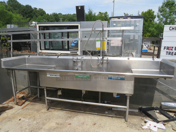 One Stainless Steel 3 Compartment Sink With 2 Faucets, Hose Sprayer, R/L Drain Board, R/L And Back Splash, And Over Head Dual Pot Rack. Sink 24X26X11. 131X30X44. - Image 1 of 3